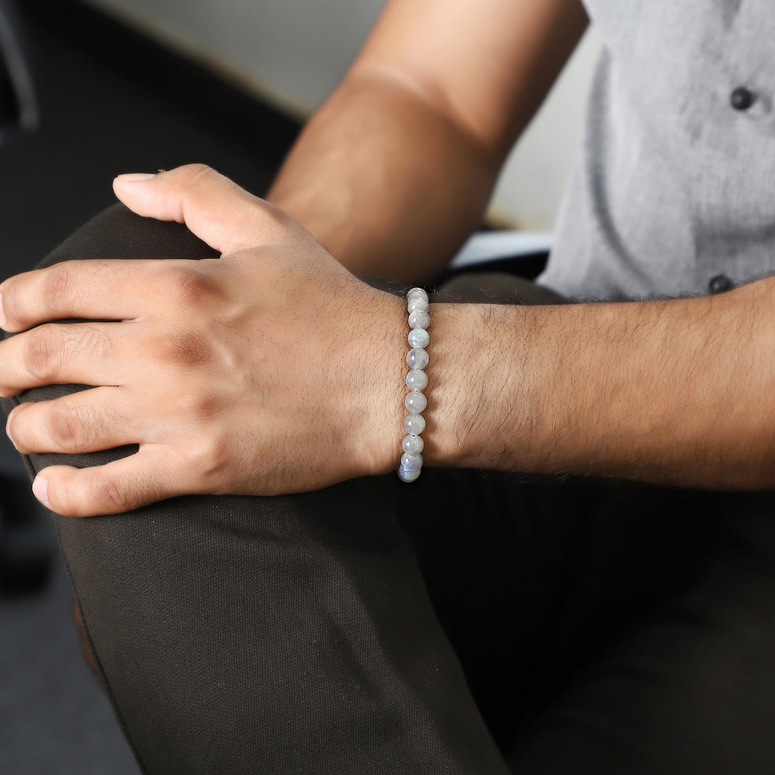 A close-up view of a bracelet made with smooth round labradorite gemstone beads, showcasing their captivating gray hues.