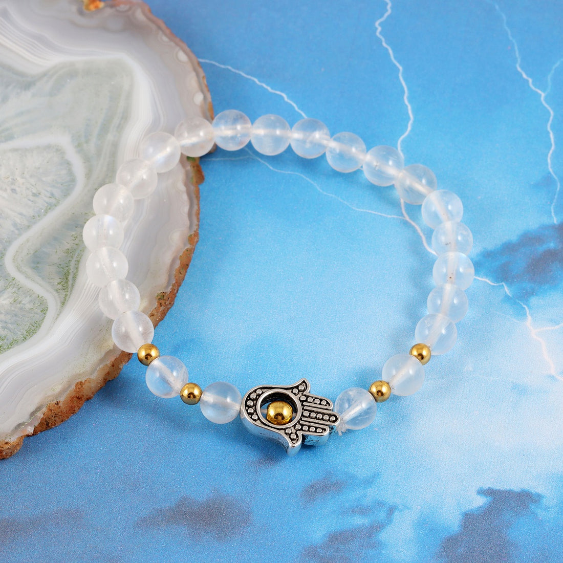 A bracelet adorned with smooth round Rainbow Moonstone beads, reflecting iridescent shades of white and promoting intuition and emotional balance.