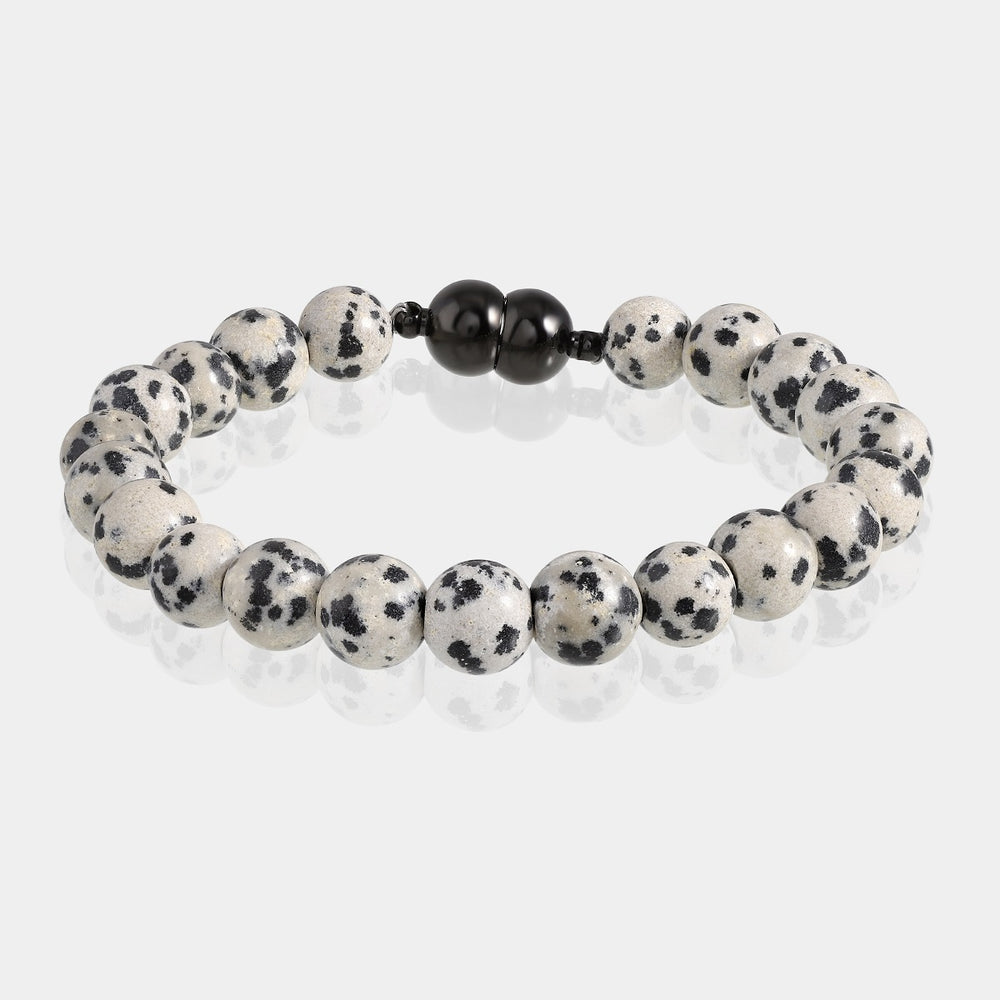 A close-up of a handmade bracelet featuring smooth round Dalmatian jasper gemstone beads with white backgrounds adorned by captivating black spots.