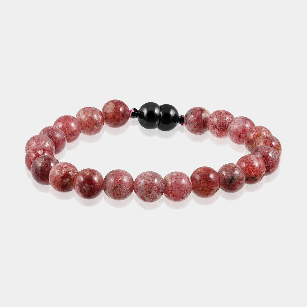 A close-up of a handmade bracelet featuring smooth round strawberry quartz gemstone beads, showcasing their delicate red hue.