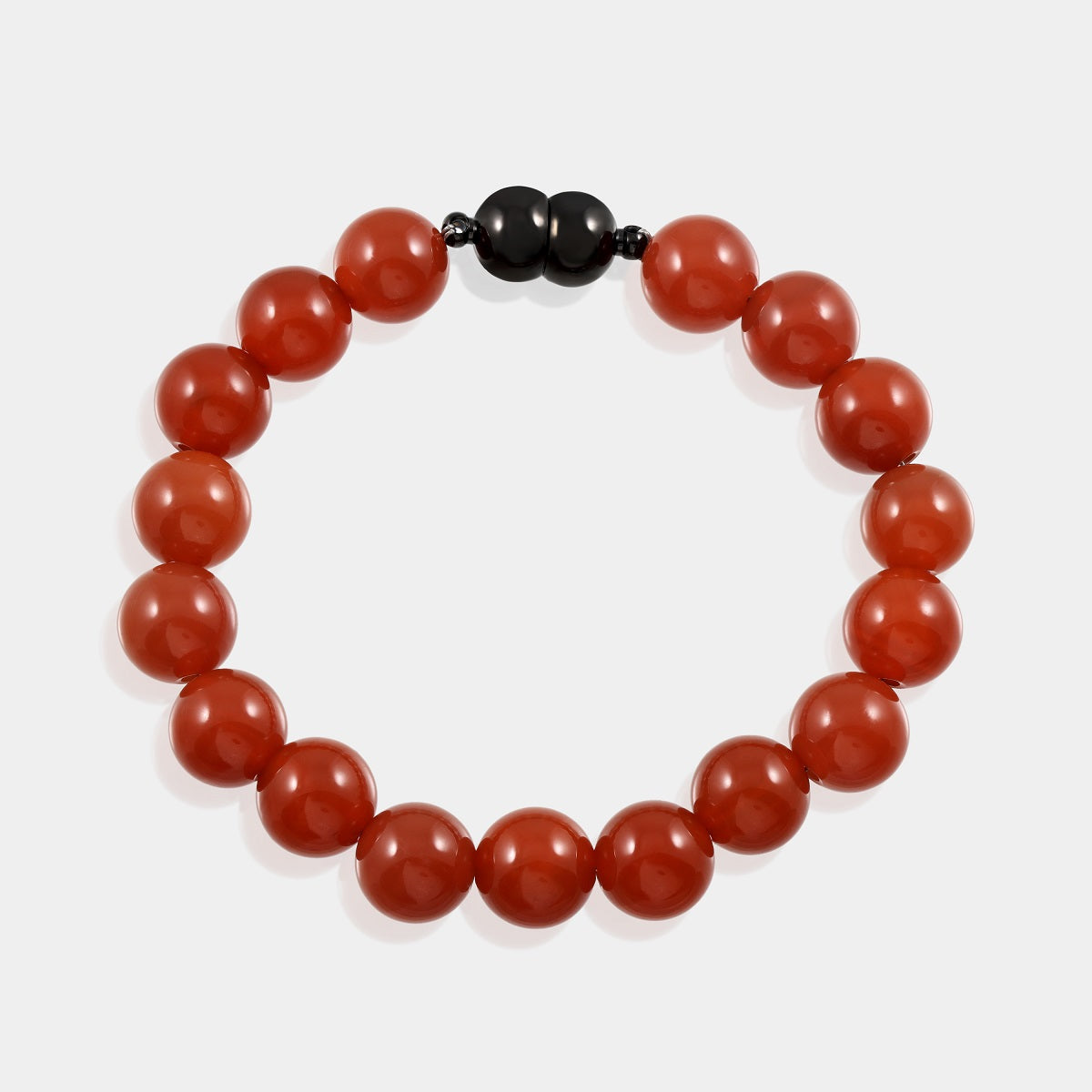 A detailed shot of the magnetic lock mechanism on the red onyx gemstone bracelet, highlighting its functional design with brass accents.