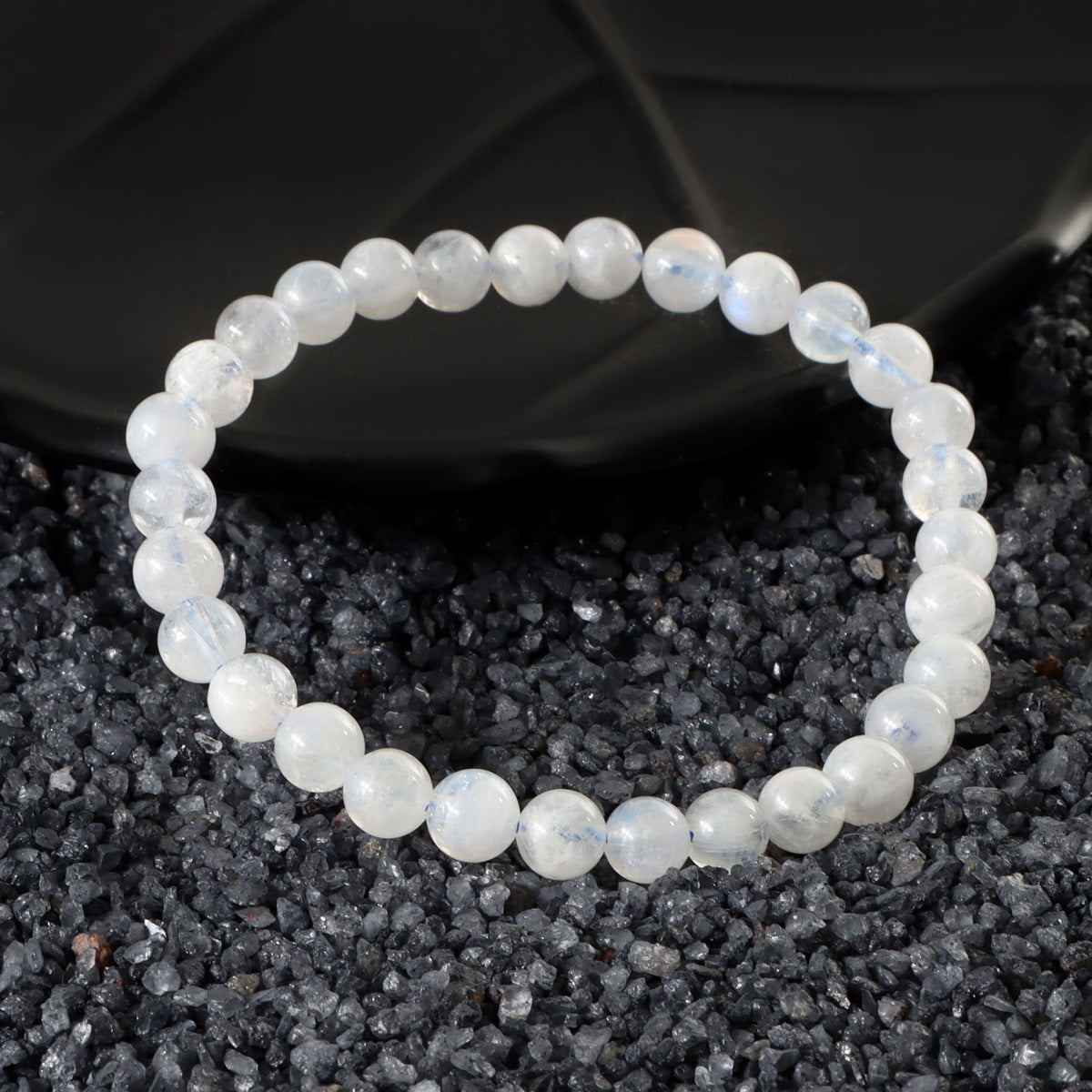 Detailed view of a 6mm Rainbow Moonstone bead, showcasing the iridescent hues and ethereal qualities in the bracelet