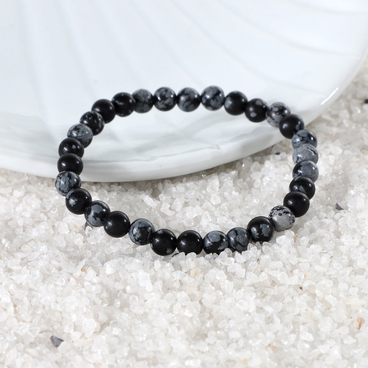 Various styling ideas for the Snowflake Obsidian Bracelet, demonstrating its versatility as a chic accessory with transformative energies of balance and centering