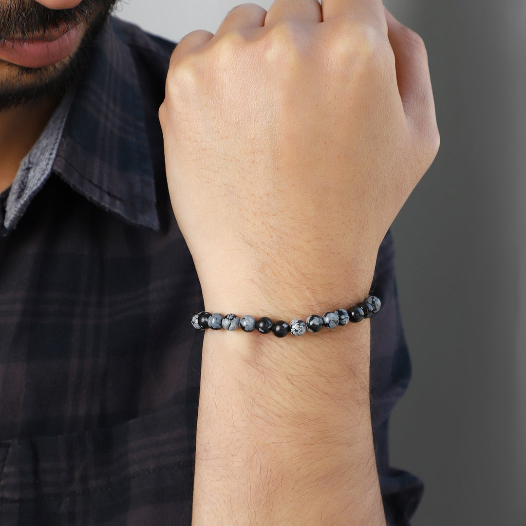 Stylish view of the Snowflake Obsidian Bracelet with 6mm smooth round beads, promoting balance and centering for a fashionable and serene accessory