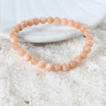 Side view of the Peach Moonstone Bracelet, showcasing its comfortable fit and the craftsmanship of the 6mm smooth round beads for a sophisticated appearance