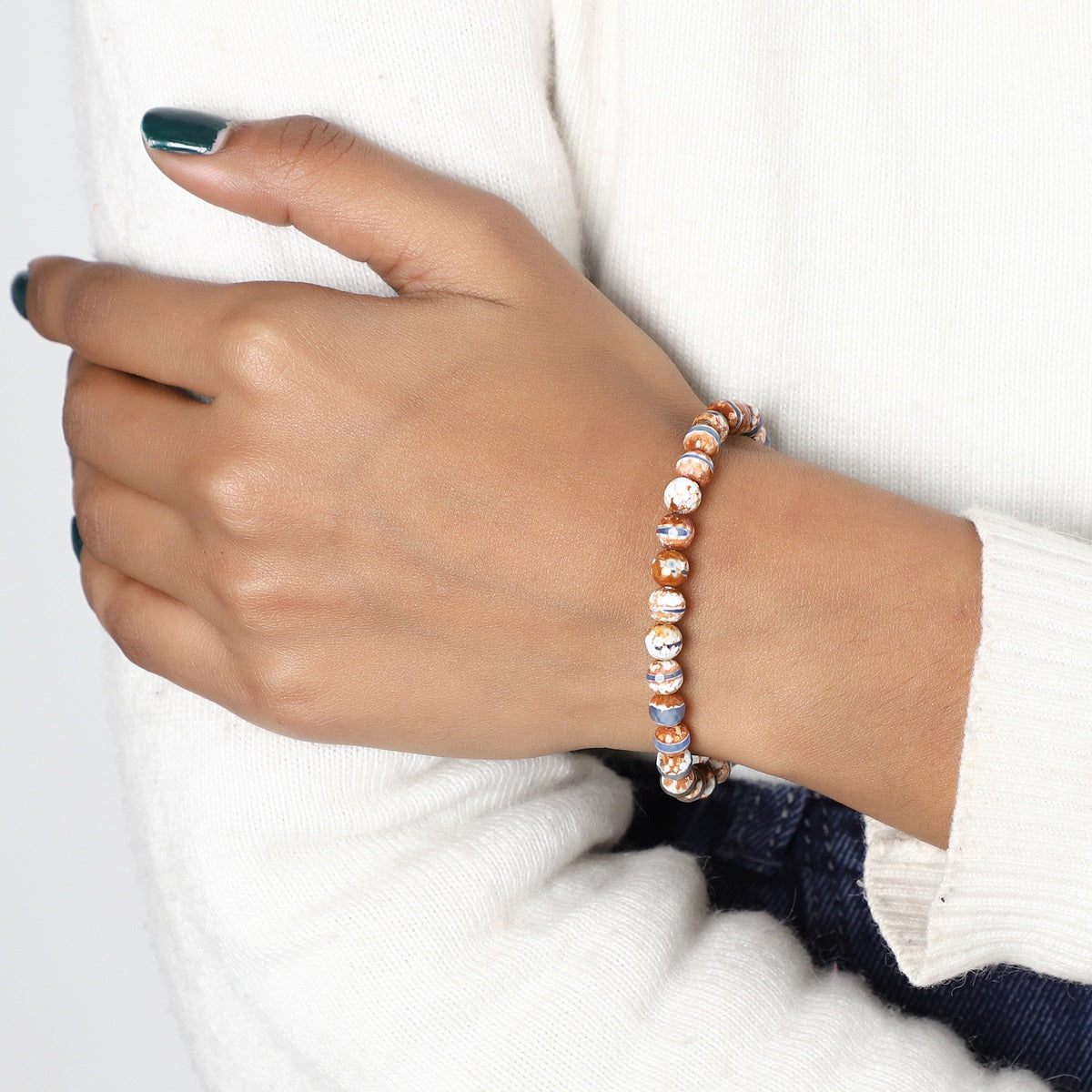 A lifestyle image featuring the Tibetan Agate Stretch Bracelet being worn, demonstrating its seamless integration into everyday fashion with a touch of spirituality