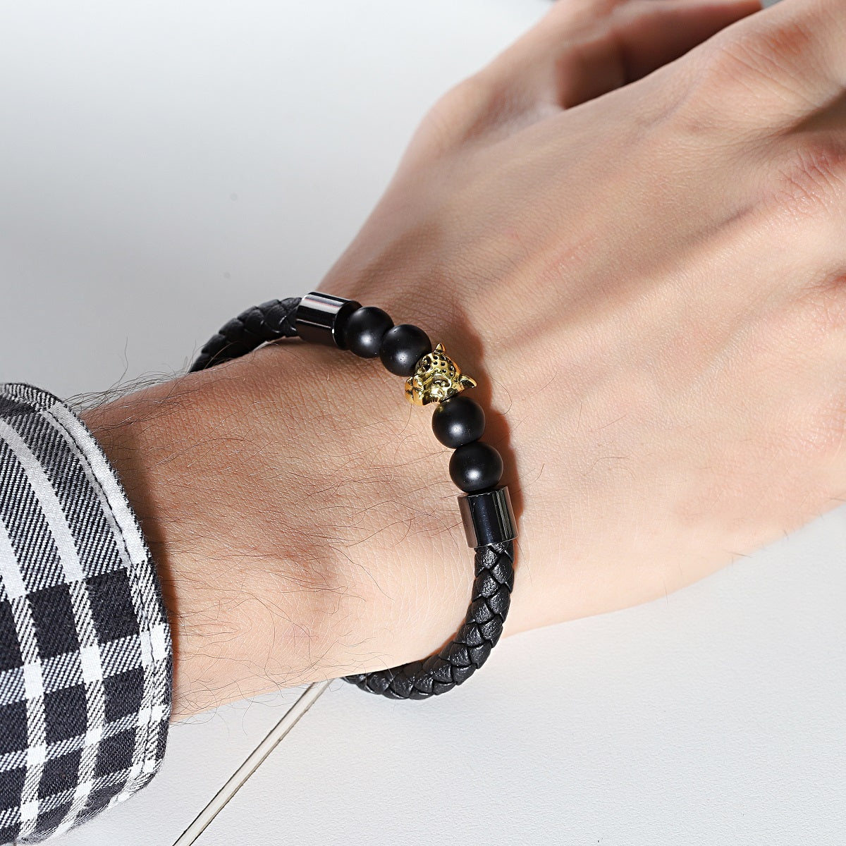 A stylish bracelet featuring sleek black jet beads and a jaguar charm on a leather strap.