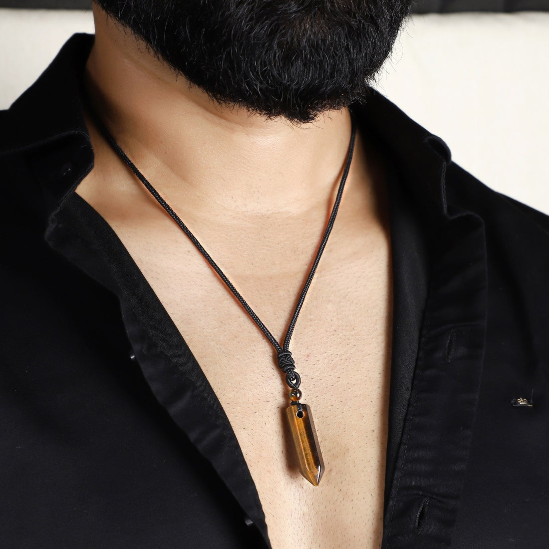 A detailed view of the artistic and intricate wrapping design that surrounds the Tiger's Eye gemstone, adding a touch of elegance to the pendant necklace.