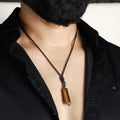 A stunning pendant necklace featuring a natural Tiger's Eye gemstone wrapped in an intricate design.
