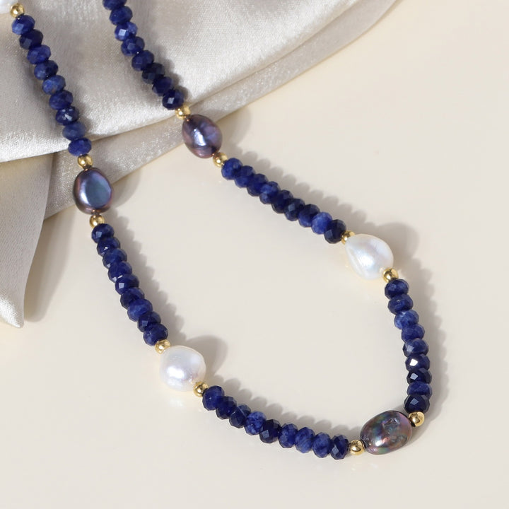 faceted rondelle Lapis Lazuli gemstone beads in vibrant blue color. Smooth tumble-shaped Pearl beads in white and black, adding elegance and grace to the necklace.