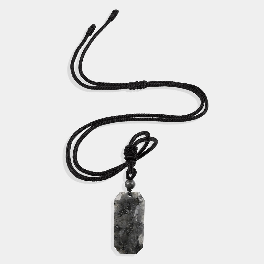 A close-up view of the pendant necklace showcasing the smooth baguette-shaped larvikite gemstone wrapped with an adjustable rope necklace, displaying its captivating blend of black and gray tones.