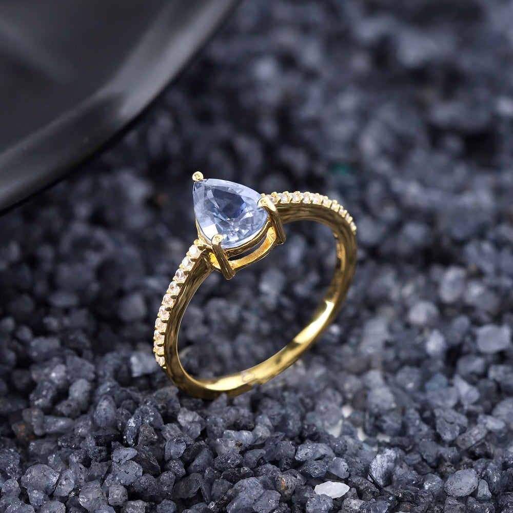 Detailed shot focusing on the secure prong setting of the 1.55ct pear-shaped Blue Sapphire, emphasizing the craftsmanship that allows its deep blue hues to shine.